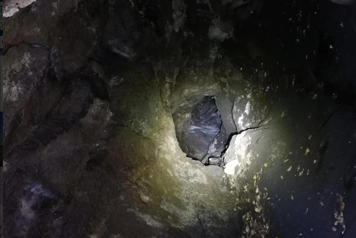 eine dunkle Höhle mit einem Loch im Boden