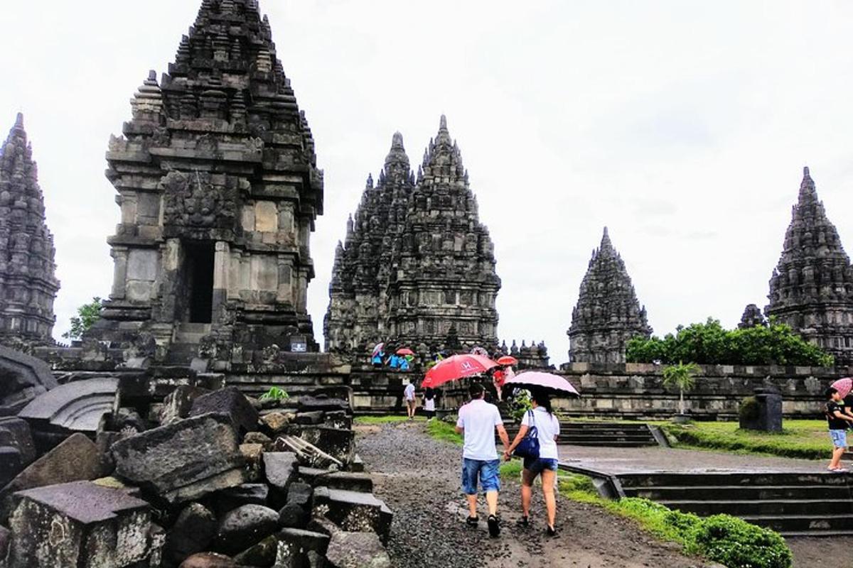 due persone con gli ombrelli che camminano davanti a un tempio