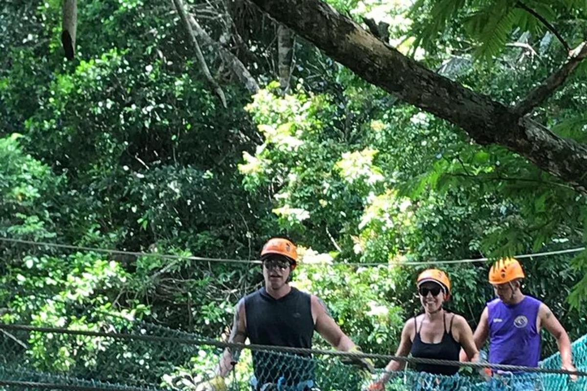 three men walking across ropes in the forest