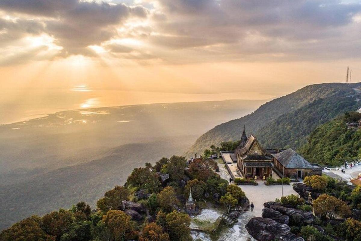 an image of a house on a hill with the sun setting