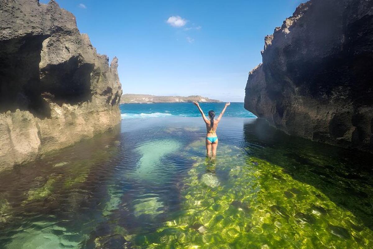 a woman standing in the water between two rocks
