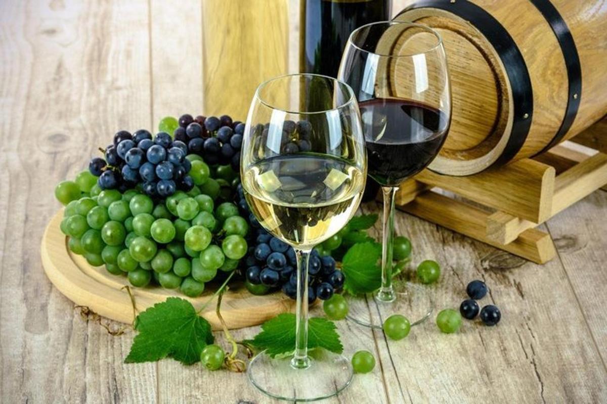 duas taças de vinho ao lado de um cacho de uvas