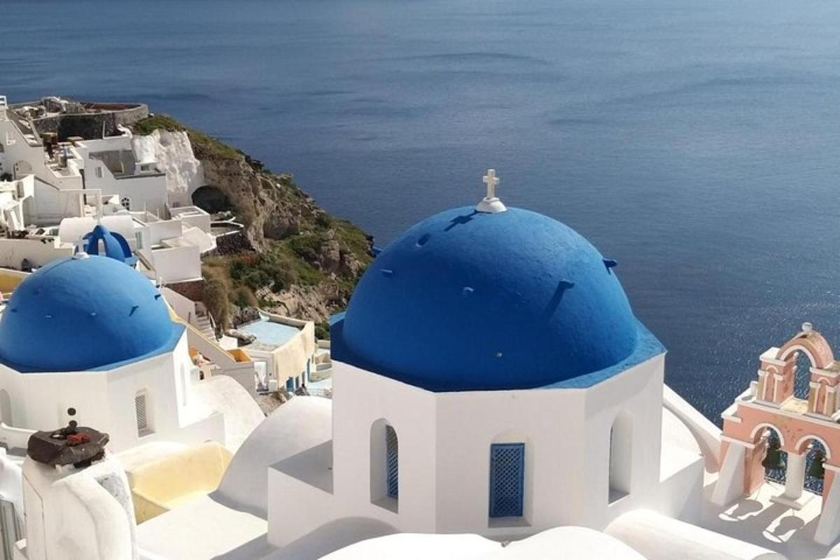un gruppo di edifici bianchi con cupole blu e l'oceano