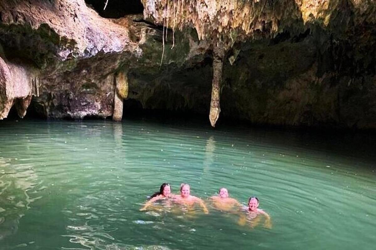 tres persones nedant a l'aigua prop d'una cova