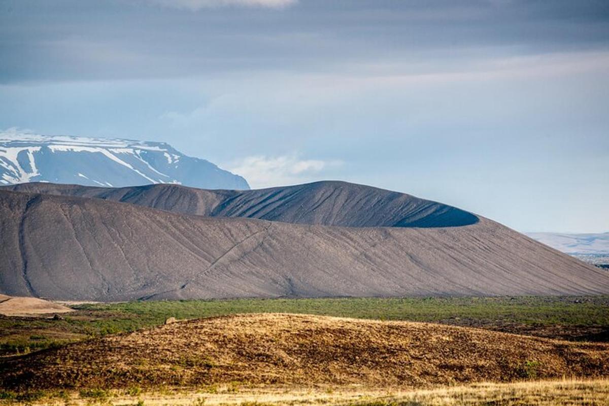 stór brún hæð með fjalli í bakgrunni
