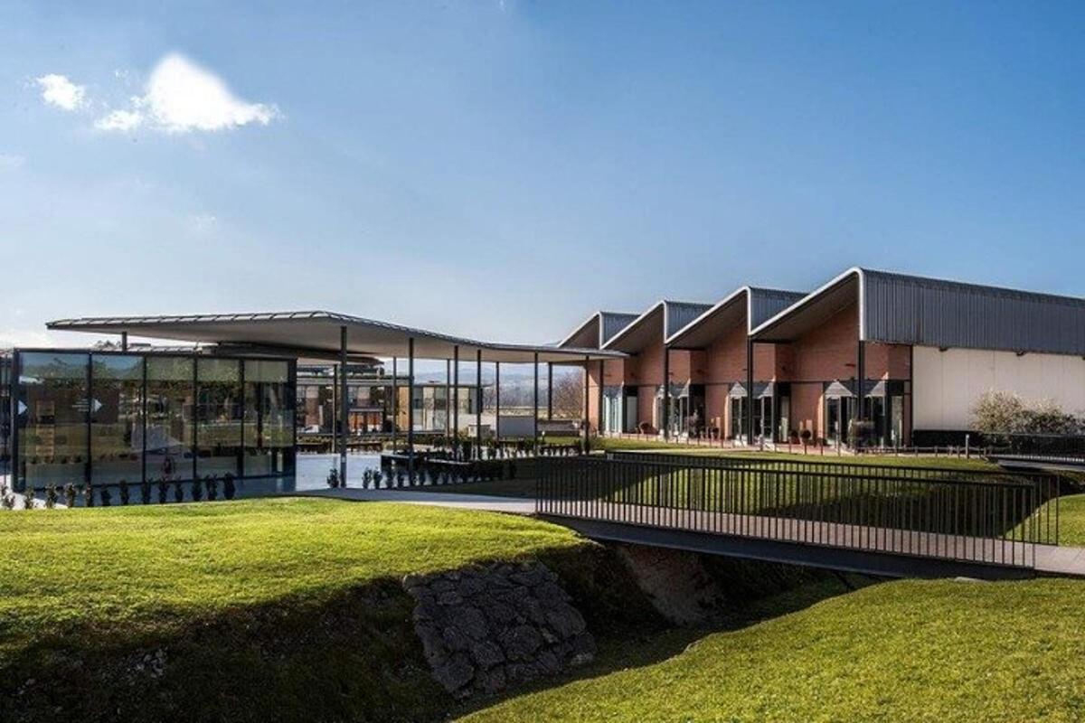 un grande edificio con un campo erboso di fronte
