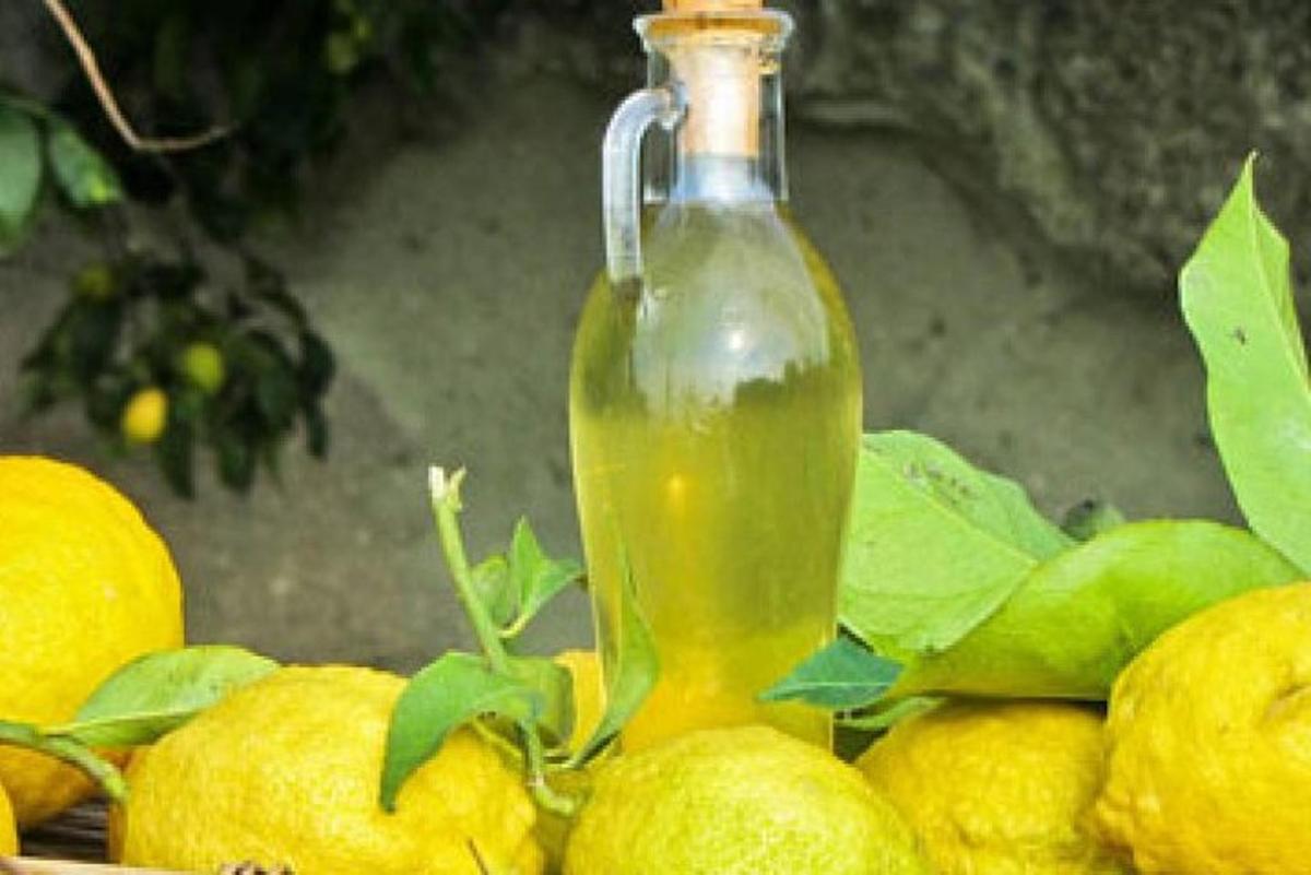 láhev zelené tekutiny sedící na hromadě citronů