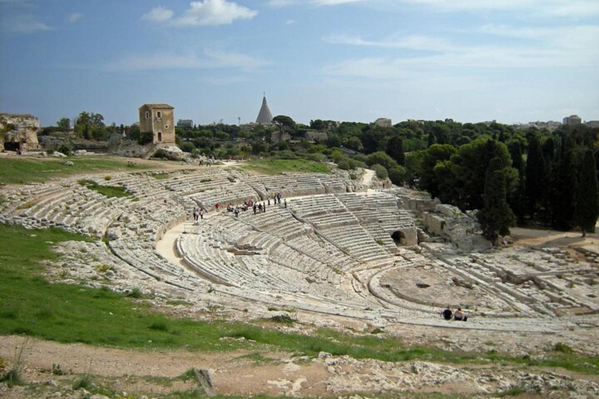 ένα αρχαίο αμφιθέατρο με ανθρώπους που στέκονται μέσα σε αυτό