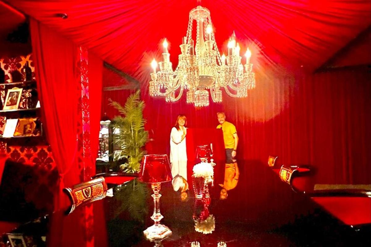 a bride and groom standing in a red room with a chandelier