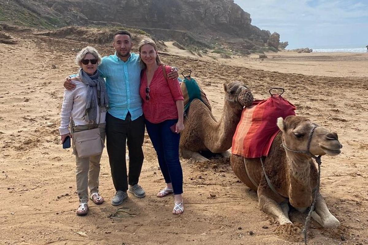 Dos mujeres y un hombre posando junto a un camello