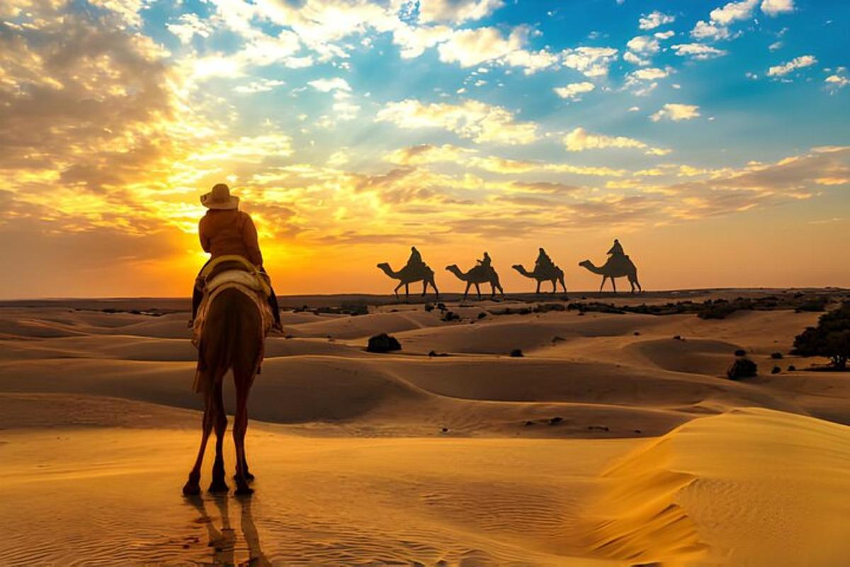 Un hombre montado en un camello en el desierto al atardecer