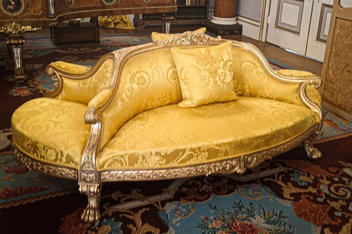 en gullsofa som sitter på et teppe i et rom