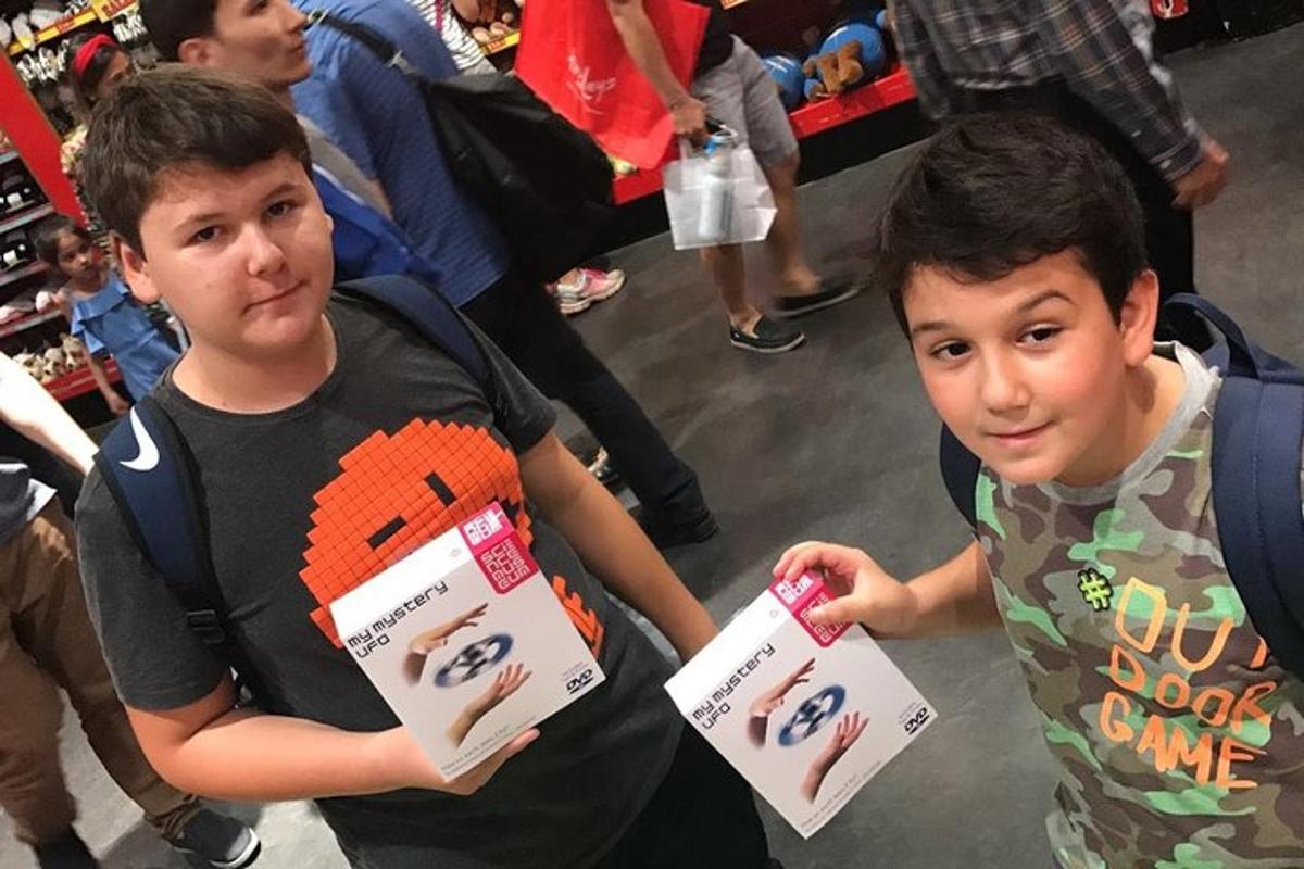 Dos niños pequeños de pie en una tienda sosteniendo cajas