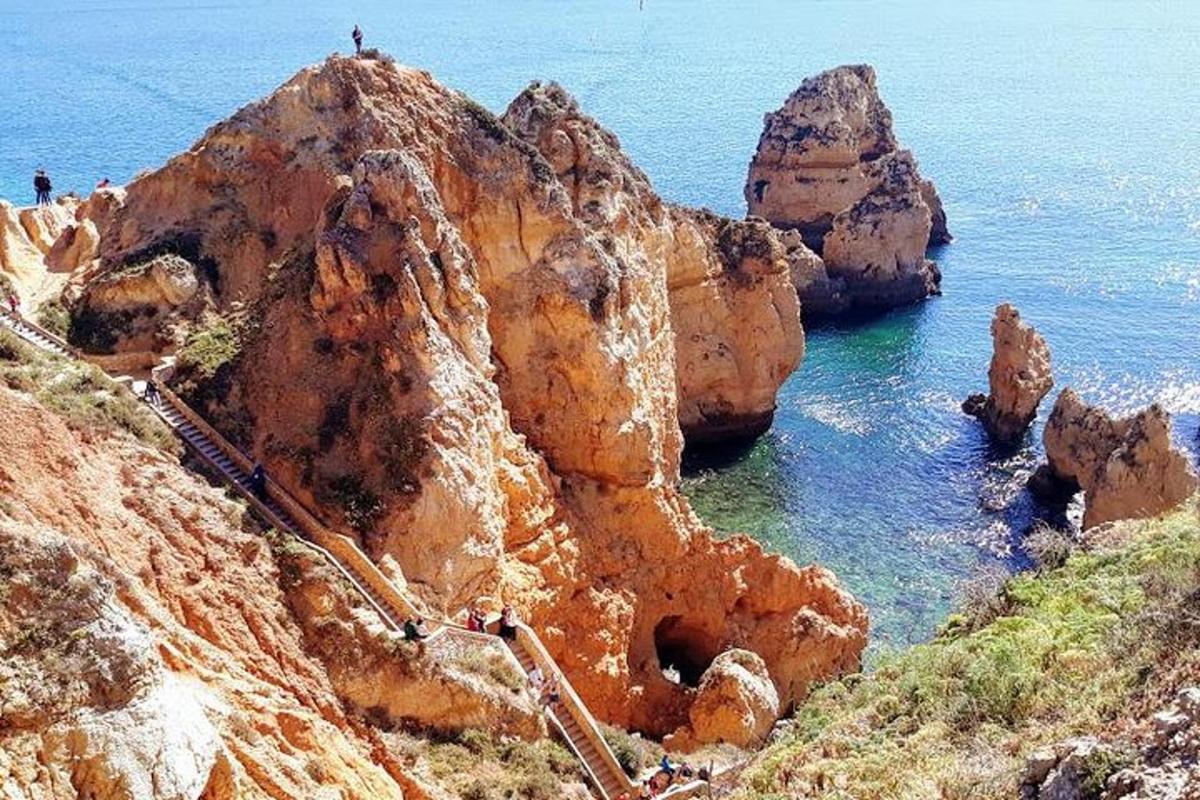группа людей, стоящих на скалистой горе у океана