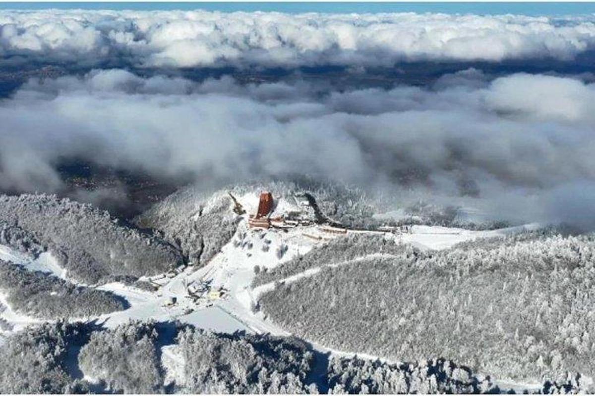 eine Luftaufnahme eines schneebedeckten Berges mit Wolken