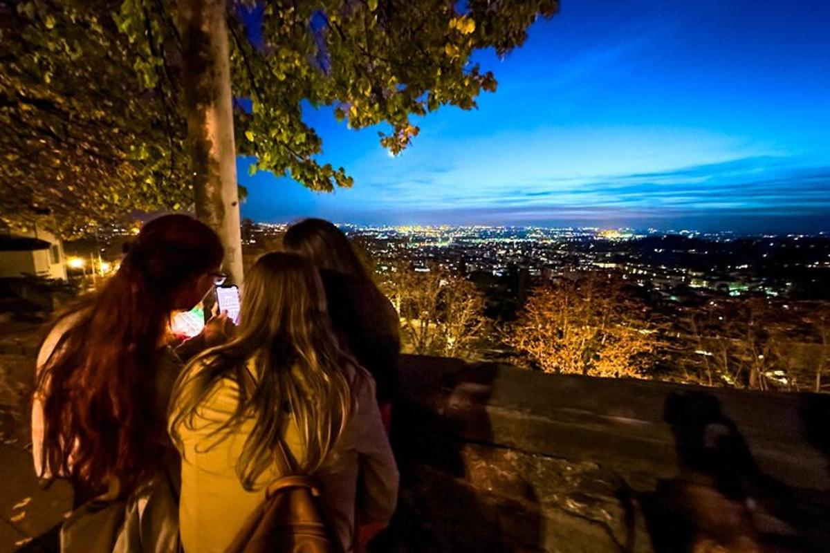 three women standing on a ledge looking at a city at night
