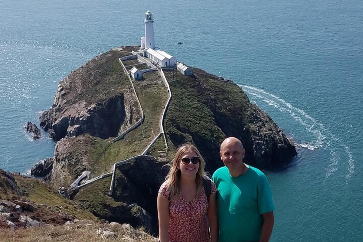 a man and woman standing in front of a lighthouse