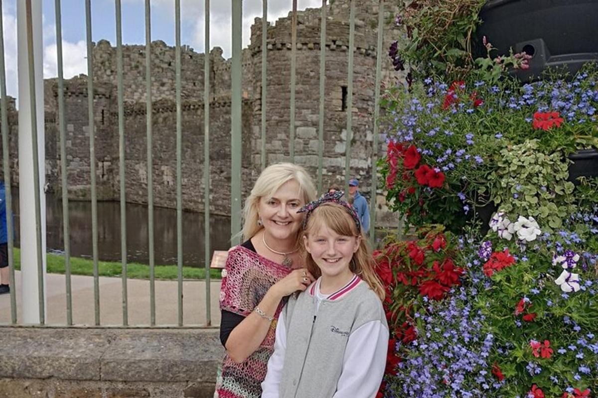 a woman and a young girl standing in front of flowers