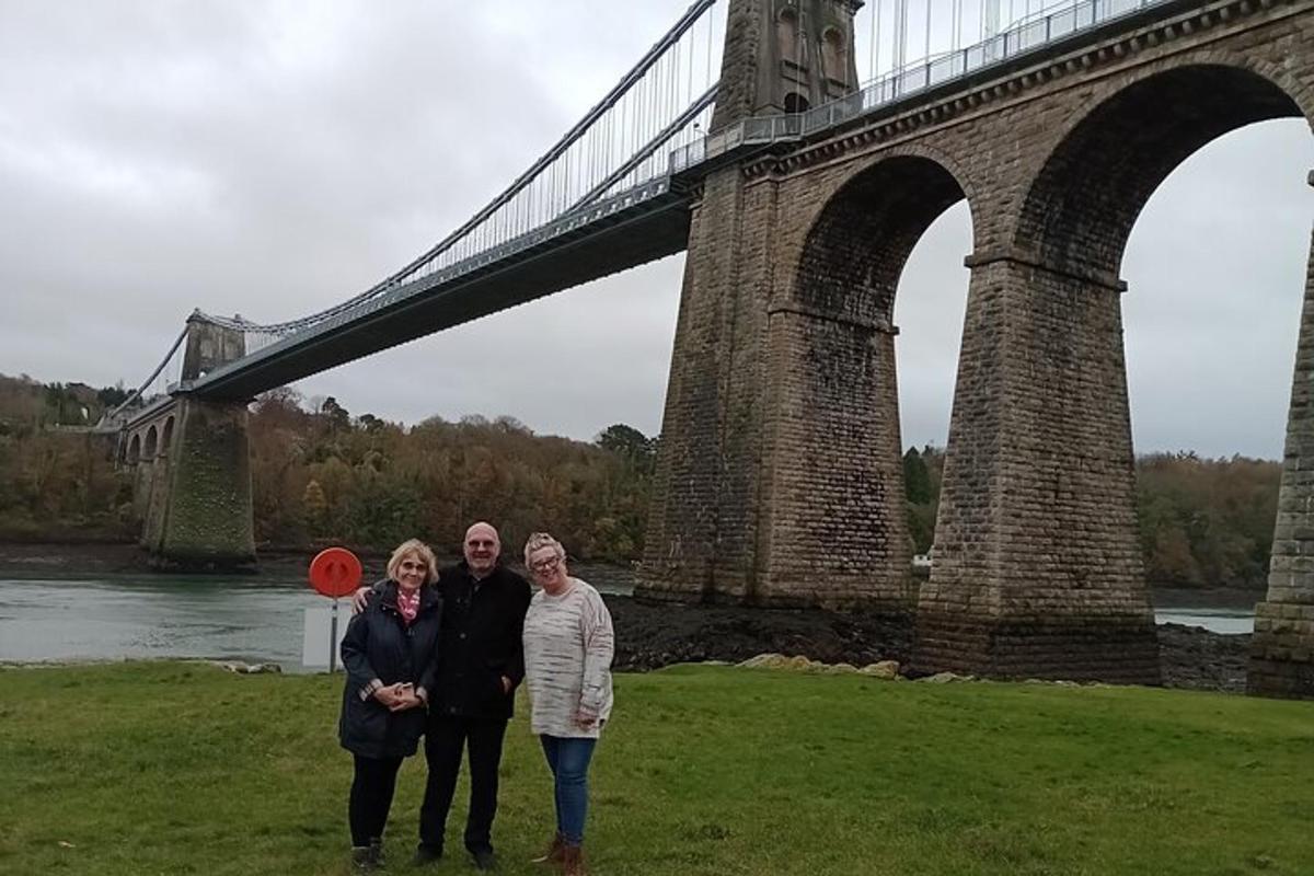a group of three people standing in front of a bridge