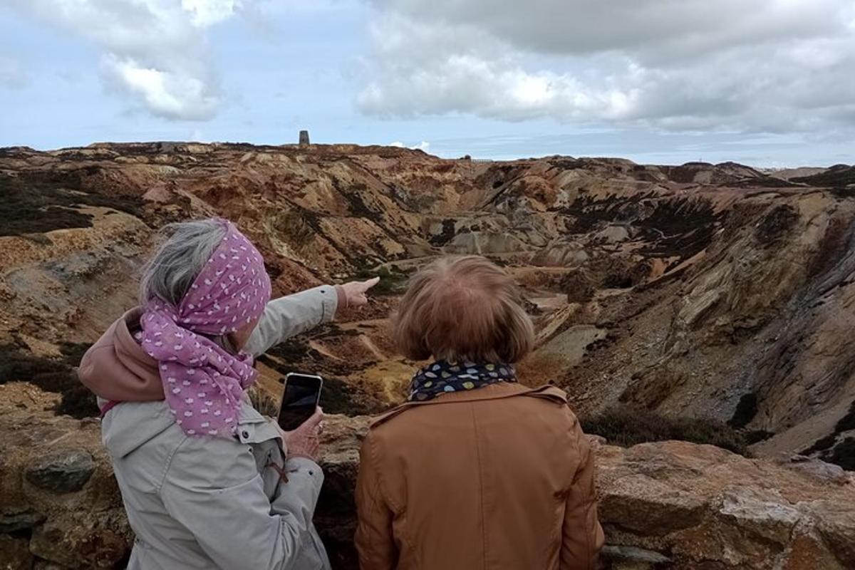 two people sitting on a cliff looking at a canyon