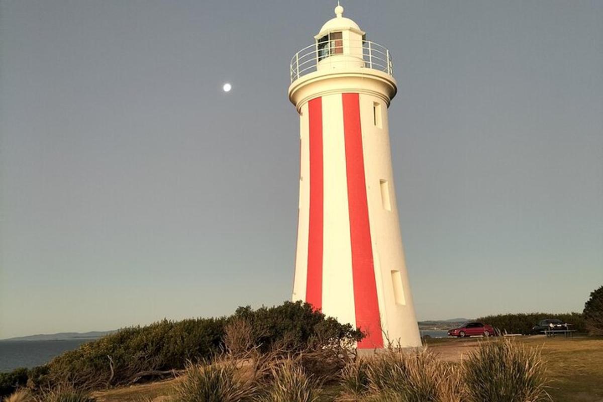 a red and white lighthouse sitting on top of a hill