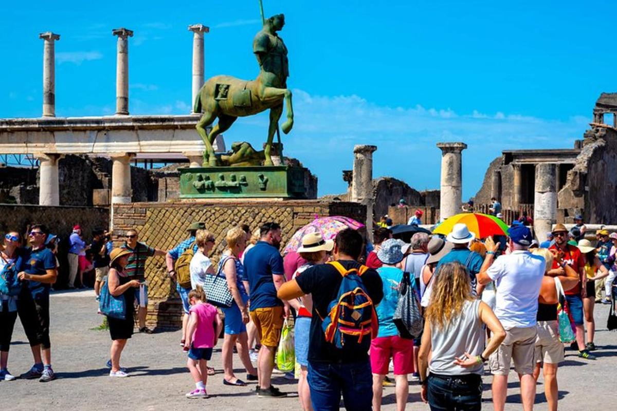 cilvēku pūlis, kas stāv statujas priekšā