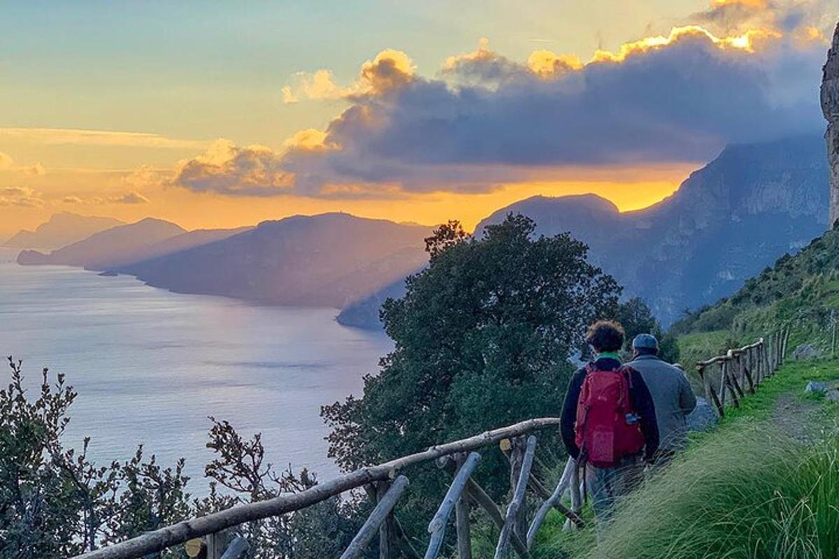 duas pessoas caminhando em uma colina com vista para o oceano
