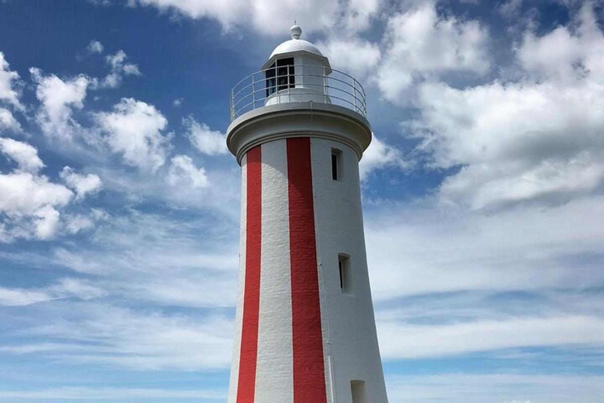 a red and white lighthouse with a sky in the background