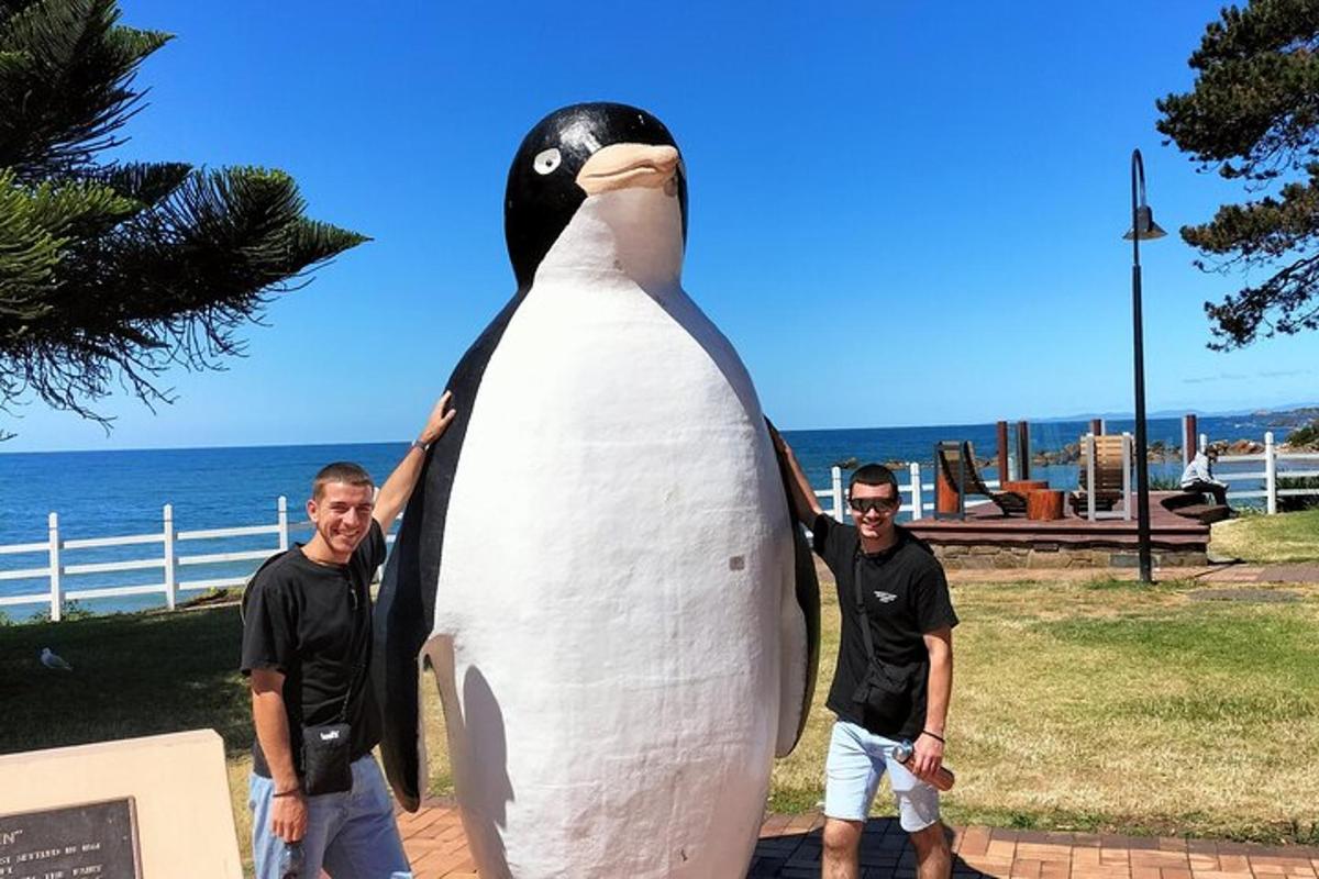 two men standing next to a large statue of a penguin
