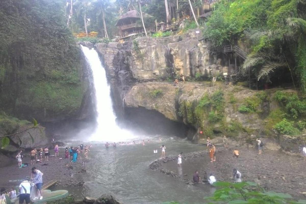 un grup de persones dempeus a l'aigua prop d'una cascada