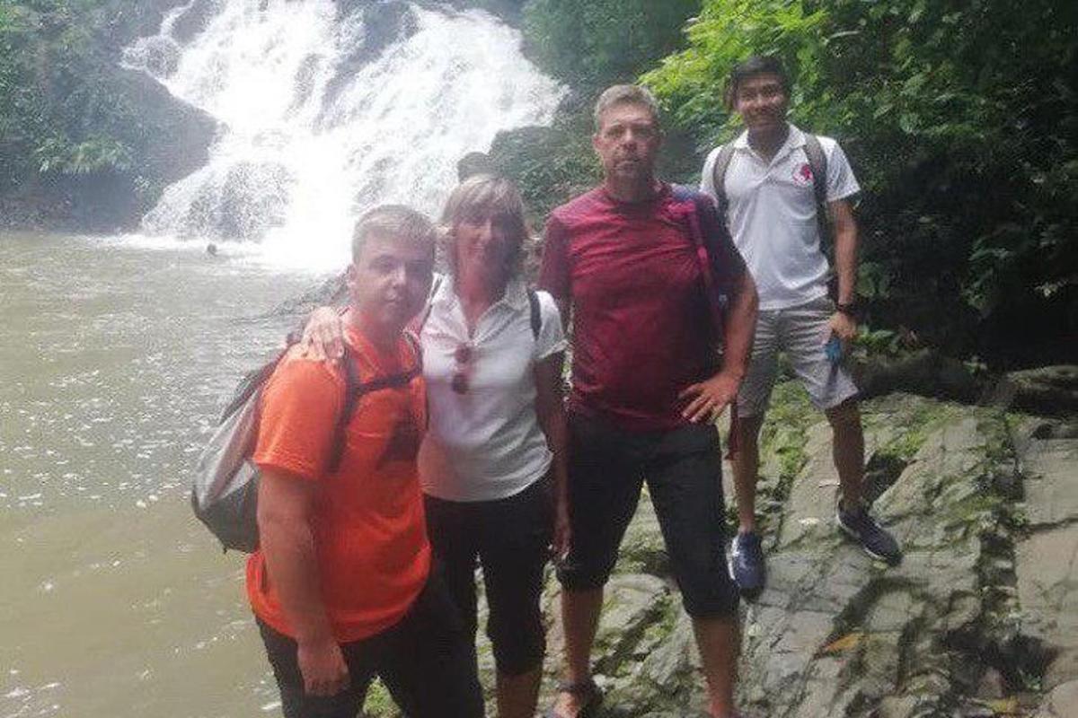 um grupo de pessoas em pé ao lado de uma cachoeira