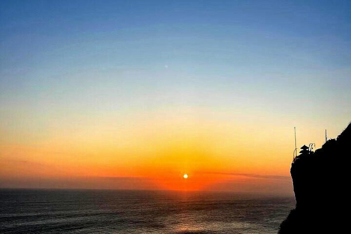 una posta de sol sobre l'oceà amb el sol al cel