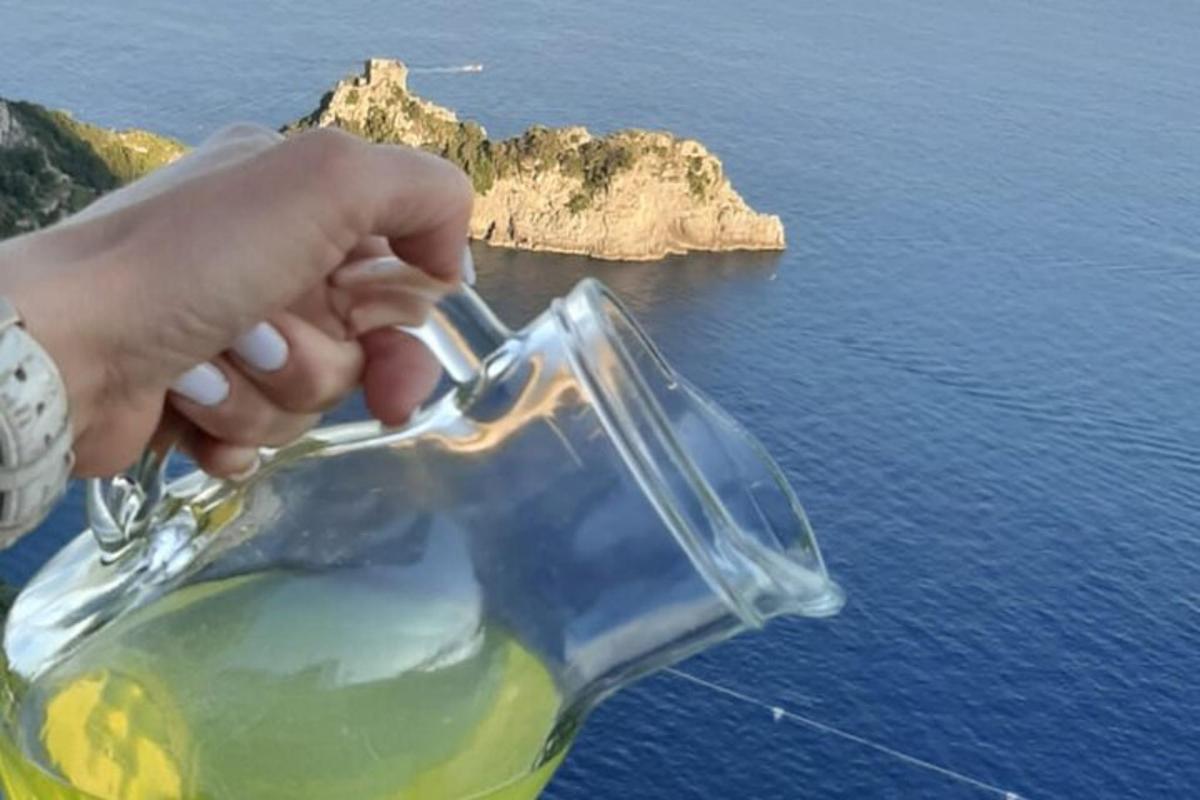 ruka držící skleněnou nádobu s výhledem na oceán