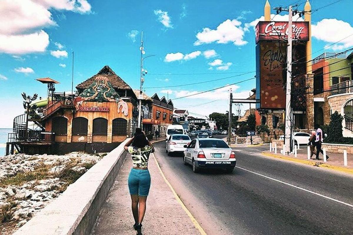 una donna che cammina lungo un marciapiede accanto a una strada