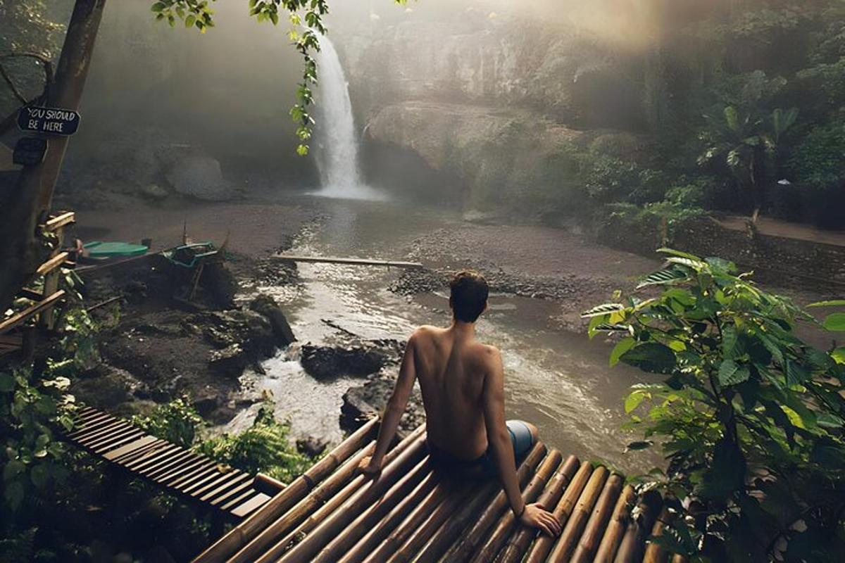 seorang lelaki duduk di atas jambatan melihat air terjun