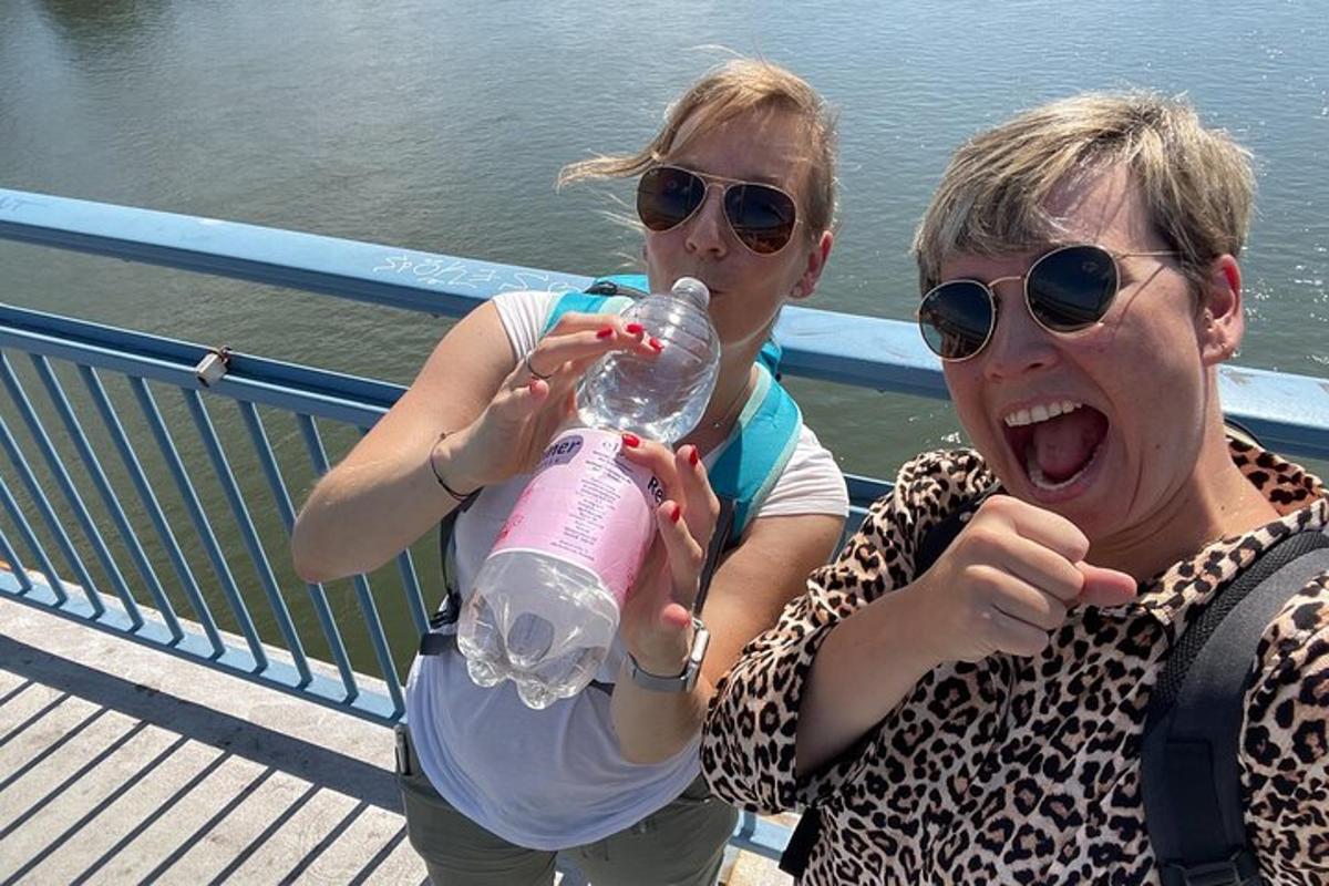 Divas sievietes sēž uz tilta un dzer no ūdens pudeles