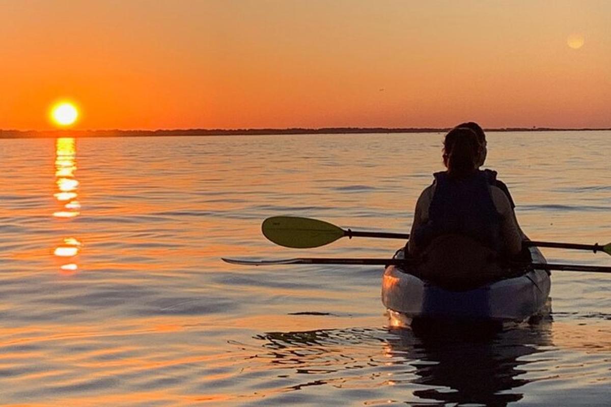 Una mujer en un kayak en el agua al atardecer
