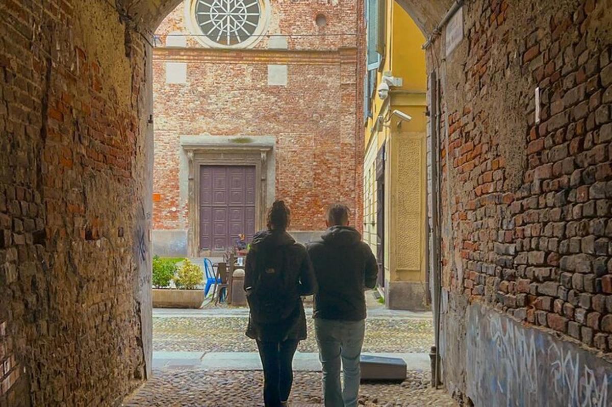 two people walking down an alley with a clock on a building