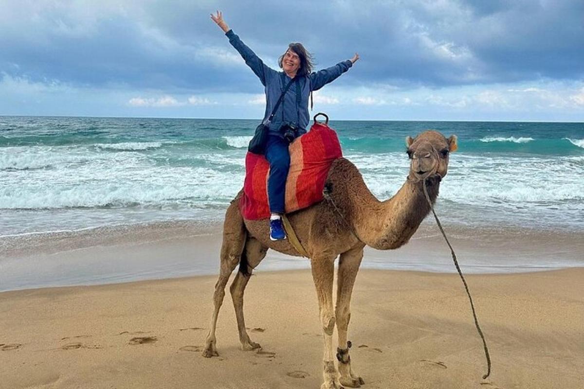 a woman riding a camel on the beach