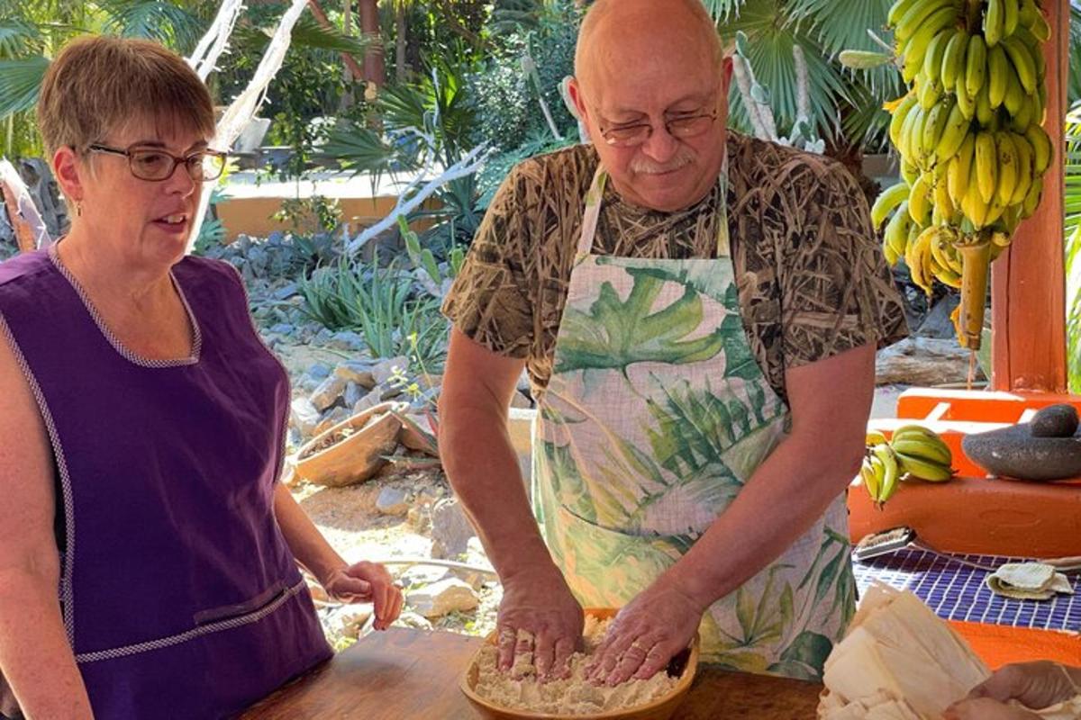 a man and a woman in an apron making a pizza