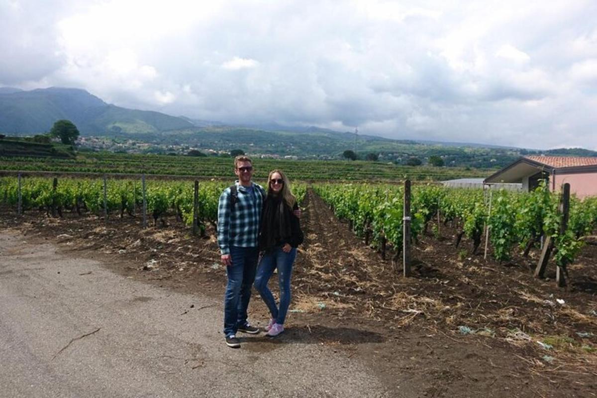 Un hombre y una mujer de pie frente a un viñedo.