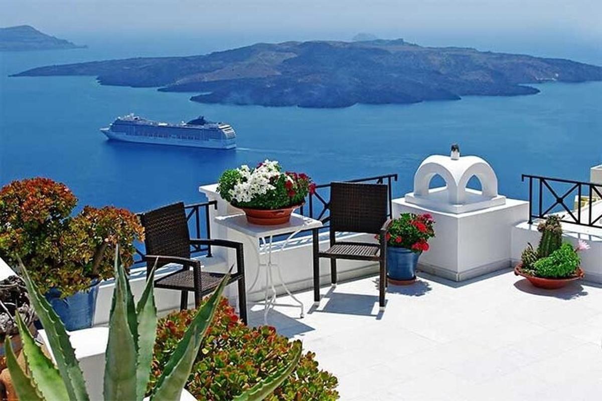 a balcony with chairs and a cruise ship in the water