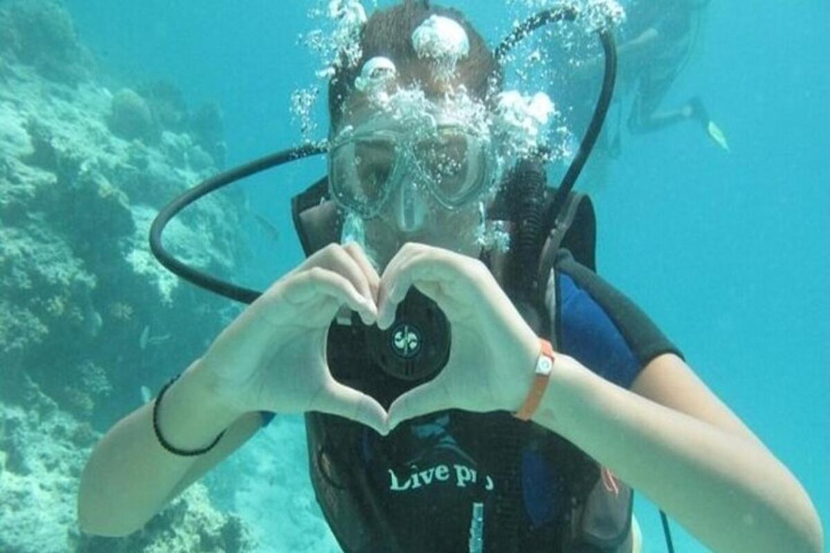 una donna che fa un cuore con una macchina fotografica in acqua