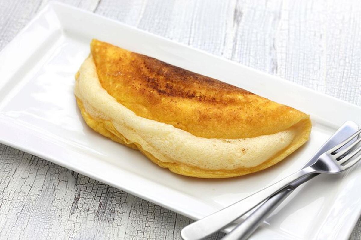 un pezzo di pane su un piatto bianco con una forchetta e un coltello