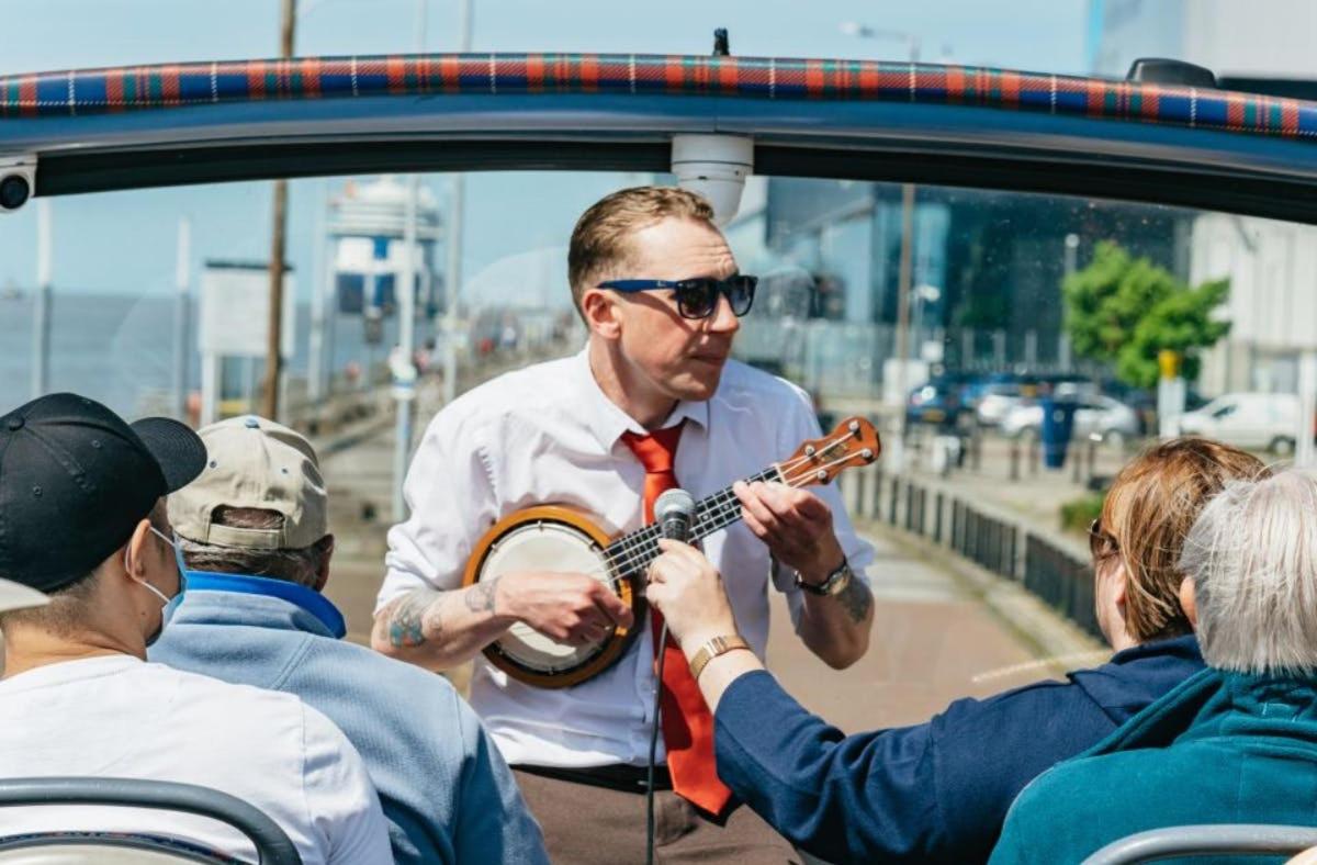 a man in a tie playing a guitar in a car