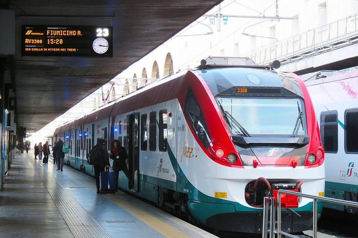 pociąg wjeżdżający na stację kolejową, do której wsiadają ludzie