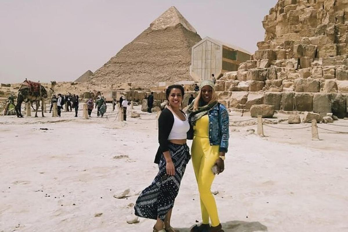 two women are standing in front of the pyramids