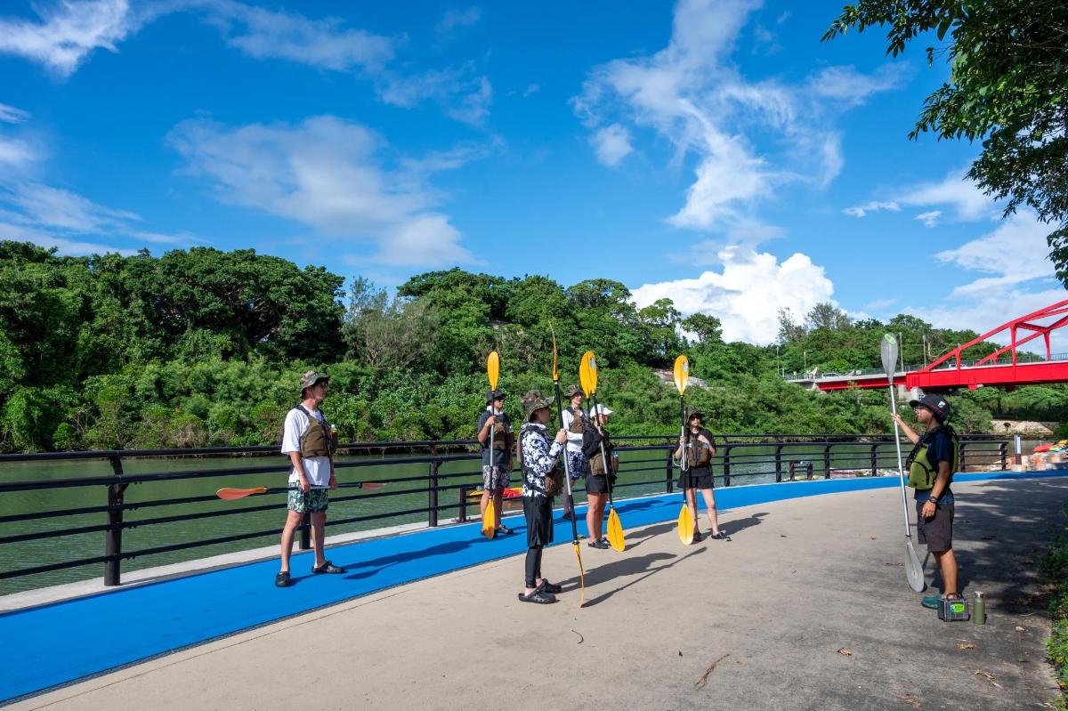a group of people standing on a bridge with paddles