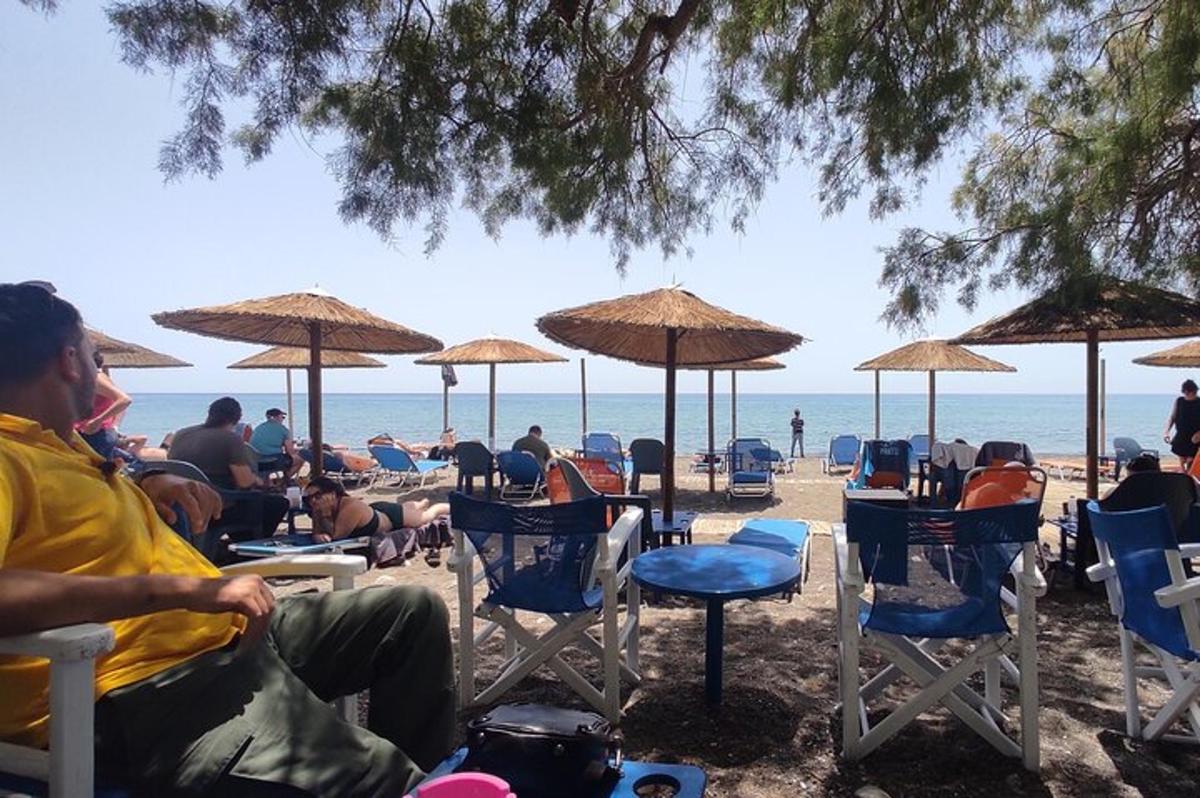 μια ομάδα ανθρώπων που κάθονται στην παραλία κάτω από ομπρέλες