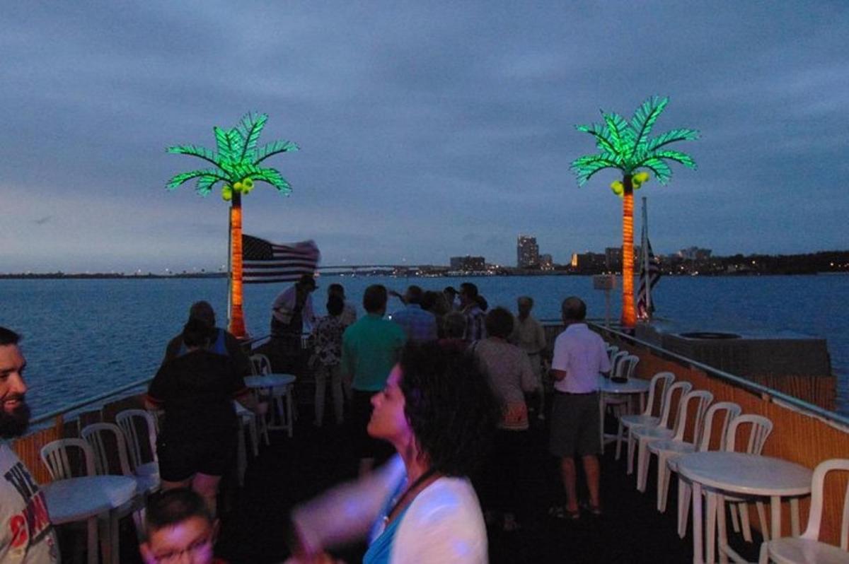 a group of people sitting on a boat with palm trees